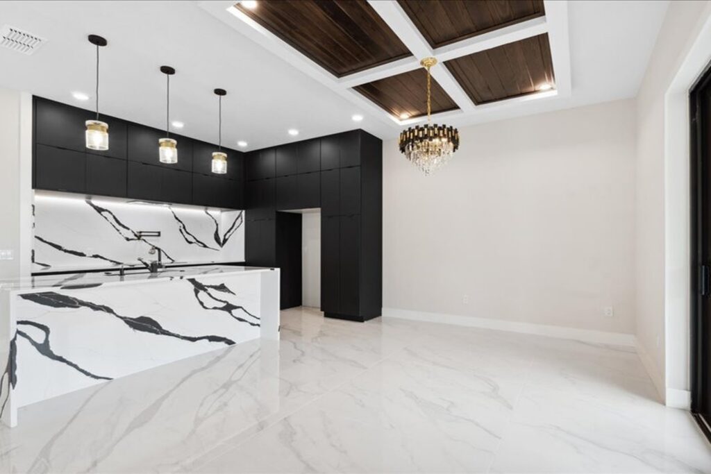 Modern kitchen with white marble waterfall island and black cabinetry in a custom home